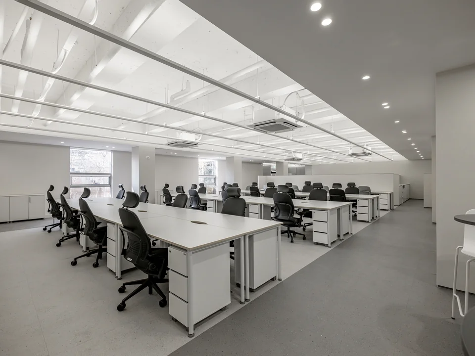Bàn làm việc sáng, nhịp tuyến tính và vách kính gọn. · RLWRLD Offices – Seoul